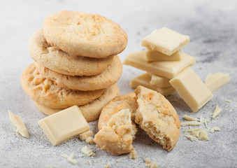 White chocolate biscuit cookies with chocolate blocks and curls on light kitchen table background.