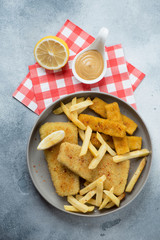 Fish and chips snack served in a grey plate, flatlay over light-blue stone background, vertical shot