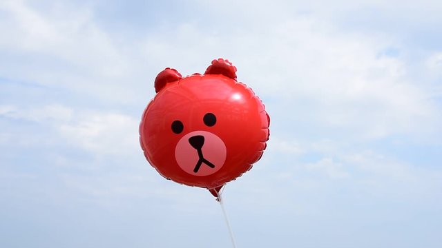 A cute bear head toy balloon swings in the air