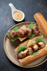 Submarine sandwiches with meatballs over dark brown stone background, vertical shot, selective focus
