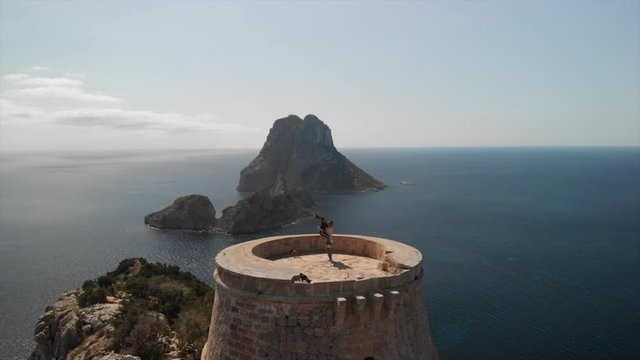 drone shot of two romantic young people kissing and  enjoying amazing views on a tower at es vedra ibiza
