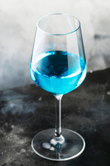 Exotic blue wine, trendy non-classical drink in wine glass on gray background