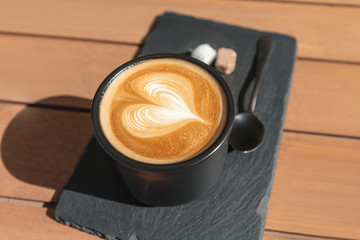 Cappuccino coffee with heart shape foam on a table in cafe