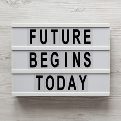 'Future begins today' words on a lightbox on a white wooden background, top view. Overhead, from above, flat lay. Closeup.