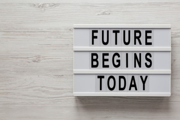 'Future begins today' words on a modern board on a white wooden background, top view. Overhead, from above, flat lay. Copy space.