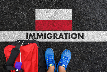 Man in shoes with bag standing next to line with word IMMIGRATION and flag of Poland on asphalt road
