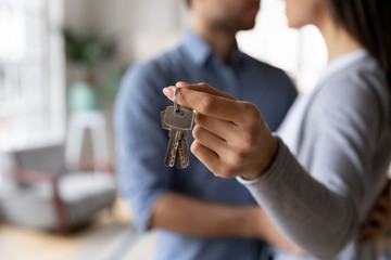 Young couple hug show house keys moving together