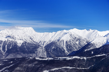 Fototapeta na wymiar Beautiful environmental view of Caucasus mountain range. Rosa Khotor ski resort. Blue sky and high mountains covered snow.