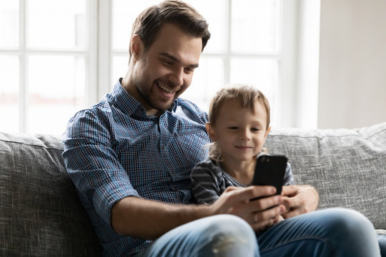 Smiling dad and little son using cellphone together