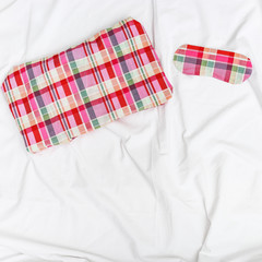 Bright pillow and sleep mask for eye on white crumpled sheet. Top  view. Flat lay.