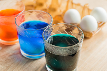 Glass with orange, blue and green paint for Easter eggs. Easter Egg decorating.