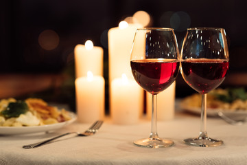Two Glasses Of Red Wine Standing On Table With Candles