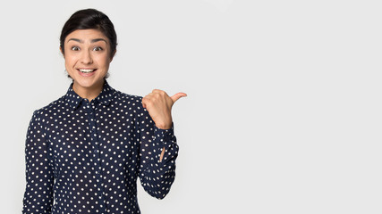 Amazed happy indian young girl pointing aside on empty copyspace.