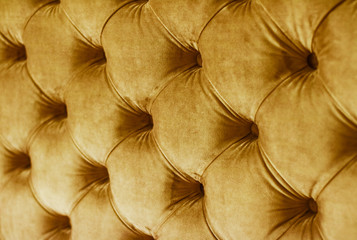 Golden luxury velour quilted sofa upholstery with buttons, elegant home decor texture and background