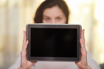 The girl is holding a tablet. The girl has a computer with a screen in her hands. Hands hold the display with an empty space.