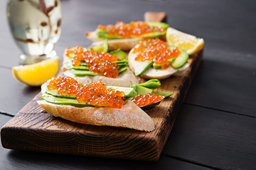 Sandwiches with salmon red caviar with sliced avocado. Sandwich for lunch. Premium food.