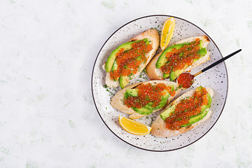 Sandwiches with salmon red caviar with sliced avocado. Sandwich for lunch. Premium food. Top view, overhead