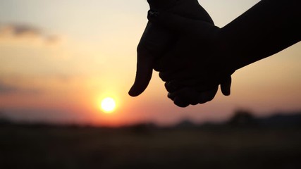 Two lovers joining Hands in 4K Slow motion. Silhouette of Man and Woman holding hands over the Sunset Background. Couple Trust, Love and Valentine's Day concept.