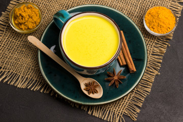 Herbal therapy concept.  Golden latte with ingredients for cooking: ginger and turmeric powder, turmeric paste, cardamom, cinnamon sticks, star anise