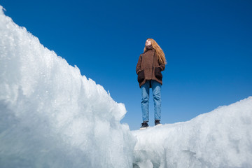 A woman on the background of broken ice covering the lake.