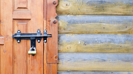 Old wooden door with a black metal bolt. Close up view of a lock and latch on a wooden door. Rustic wooden metal door latch. This sliding lock can be used on awnings, on desktops or on fences.