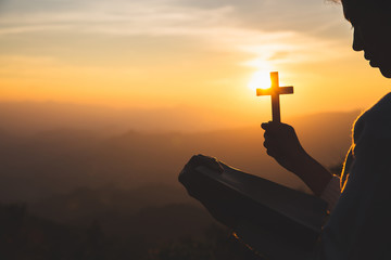 A women is praying to God on the mountain. Praying hands with faith in religion and belief in God...