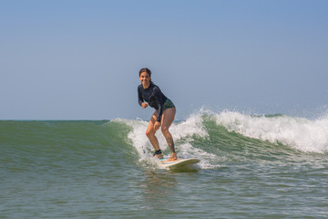 A girl surfing a wave on a sunny day in Asia