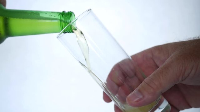 Man Fills a Glass Full of Beer from a Bottle