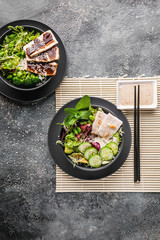 Asian food. Chinese cuisine. Stir fry rice, vegetables and meat with nutty spicy sauce on a bamboo mat. Vertical shot. Top view