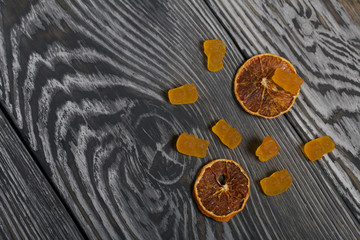 Jelly chewing sweets. Dried slices of orange. Scattered on brushed pine boards painted in black and white.