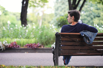 A young man walks in the park at lunch time. A man is on a walk in the city. A student in the park.