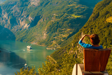 Tourist enjoy Geiranger fjord from viewpoint seat
