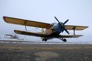 A picture from the airfield during the winter. The old biplane is standing on the runway and...