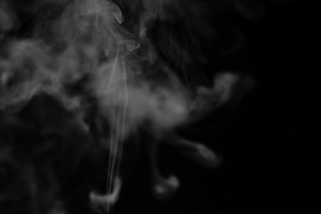 White smoke on a black background. Texture of smoke. Clubs of white smoke on a dark background for an overlay