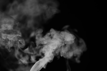 White smoke on a black background. Texture of smoke. Clubs of white smoke on a dark background for an overlay