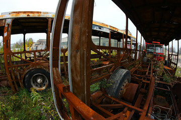 The wrecks of the buses standing on the vehicle cemetery. Waiting to be scrapped. Only rusty constructions sometimes remain. 