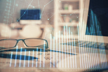 Financial chart hologram with glasses on the table background. Concept of business. Double exposure.