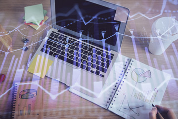 Double exposure of man's hands writing notes of stock market with forex chart.