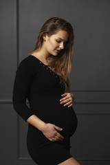 Portrait gorgeous young pregnant woman touching gently with hands her belly, she is waiting a new life