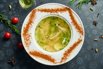 Dietary soup with chicken, boiled egg vegetables and parsley in compostion with ingridients on dark background in white bowl. Top view tasty soup. Flat lay food