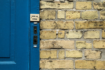 The detail of a Danish house, of its door and entrance with part of the wall. The doorbell is visible. The sheet says "Door are closed". 