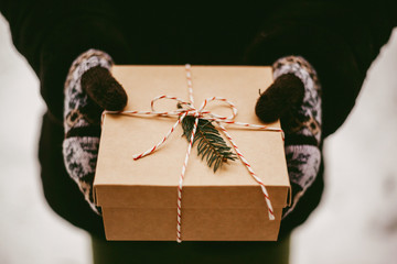 Woman's hands hold christmas or new year decorated gift box outdoor