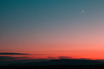 A minimalist view from the colorful sunset. Different shades of pink and blue with the small moon...