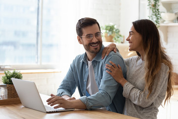 Happy young man in eyeglasses looking at laughing woman.