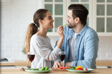 Cheerful young mixed race woman feeding beloved man vegetables.