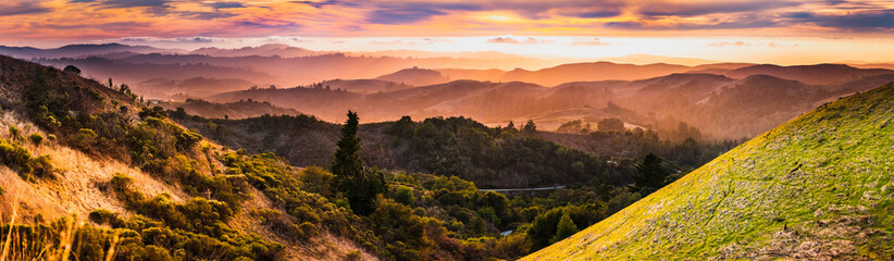 Expansive panorama in Santa Cruz mountains, with hills and valleys illuminated by the sunset light; San Francisco Bay Area, California