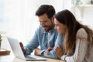 Happy young mixed race couple watching funny videos on computer.