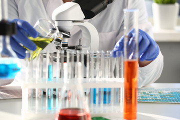 A male chemist holds test tube of glass in his hand overflows a liquid solution of potassium...