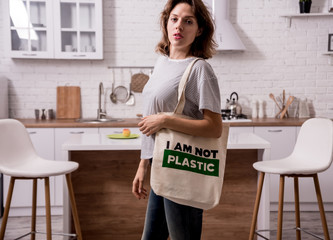 Young girl holding a cloth bag. At the kitchen. I am not plastic. Campaign to reduce the use of plastic bags. Zero waste