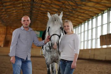 People on a horse training in a wooden arena